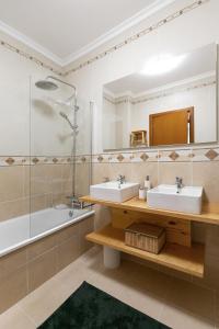 y baño con 2 lavabos, ducha y bañera. en Nazaré Modern Flat, en Nazaré