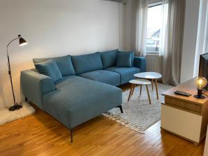 sala de estar con sofá azul y mesa en Apartman Iva, en Bijeljina