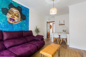 a living room with a purple couch and a painting at Apartamento céntrico y cerca de la playa in Ribeira