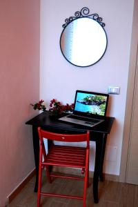 a black desk with a laptop on it with a red chair at B&B Vivere il Mare in San Vito lo Capo