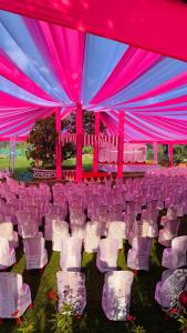 a large marquee with white chairs and pinkitures at Ashoka Lawns and Resort in Alibaug