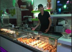 un hombre parado detrás de un mostrador en una panadería en l'angolo di Gaudì, alcoba Fascinosa, en Putignano