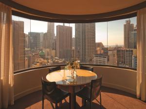 シドニーにあるアディナ　アパートメント　ホテル　シドニー　タウンホールの大きな窓のある客室で、テーブルと椅子が備わります。
