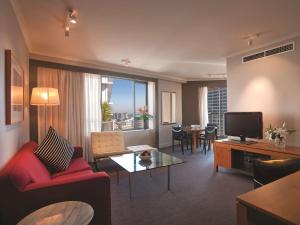 a living room with a red couch and a television at Adina Apartment Hotel Sydney Town Hall in Sydney