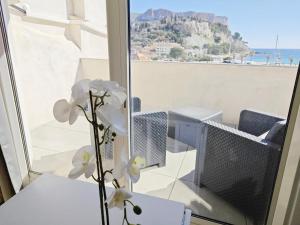 a vase with flowers on a table in front of a window at Cassis Loc - Appartement meublé in Cassis