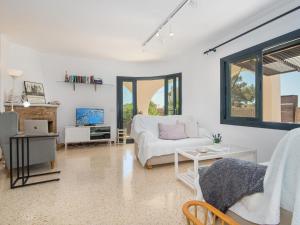 a living room with a white couch and a tv at Casa Lloc Tranquil in Cala Figuera