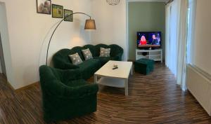 - un salon avec des chaises vertes, une table et une télévision dans l'établissement Noclegi Little Sheep, à Chojna