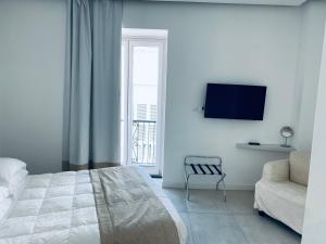 una camera con letto, sedia e TV di White 1903 a Ischia