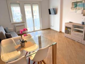 a living room with a glass table and chairs at Alghero Charming Apartments, Steps from the beach in Alghero