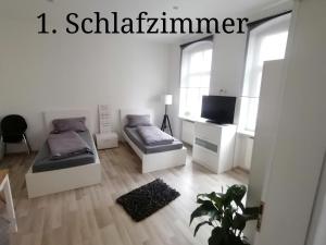 Dieses weiße Zimmer verfügt über 2 Betten und einen TV. in der Unterkunft Exklusive Ferienwohnung im Zentrum von Plauen in Plauen
