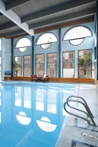 a swimming pool with chairs and windows in a building at Tonquin Inn in Jasper