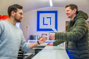 a man handing another man a piece of paper at Hostel Little Quarter in Prague