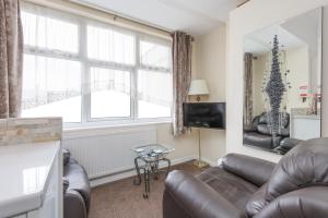 a living room with a leather couch and a large window at Beachcliffe Holiday Apartments in Blackpool