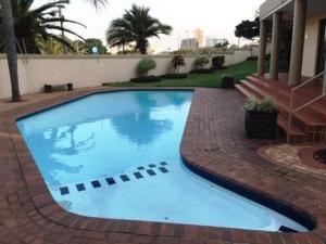 une grande piscine bleue sur une promenade en briques dans l'établissement 18 The Shades Umhlanga Rocks, à Durban
