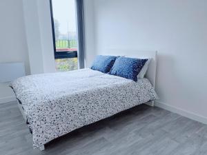 Modern House في مانشستر: غرفة نوم مع سرير ووسائد زرقاء ونافذة