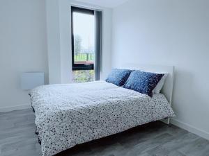 Modern House في مانشستر: غرفة نوم بيضاء مع سرير ووسائد زرقاء ونافذة