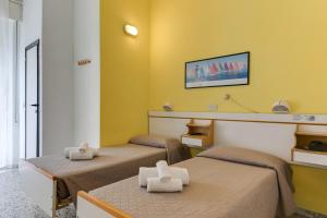 2 łóżka w pokoju z żółtymi ścianami w obiekcie Hotel Villa Merope w Rimini