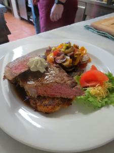 a plate of food with meat and vegetables on a table at Hotel Aquamarin in Bad Mitterndorf