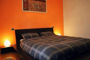 アーバノ・テルメにあるAppartamento alle Termeのオレンジ色の壁のベッドルーム1室、ベッド1台(ランプ2つ付)