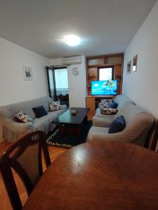 Apartment in Budva في بودفا: غرفة معيشة مع كنبتين وتلفزيون بشاشة مسطحة