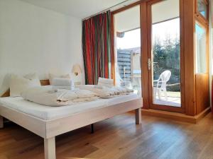 Cama blanca en habitación con puerta corredera de cristal en Alpin-Apartment-11, en Bad Wiessee