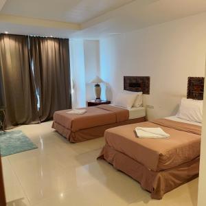 a hotel room with two beds and a table at Jomtien Hostel 3 in Jomtien Beach