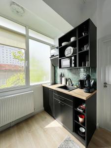 a kitchen with black cabinets and a sink and a window at Town Spot - Premium Studio - Sanador Victoriei in Bucharest