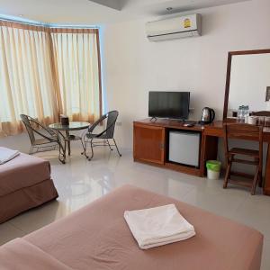 ein Wohnzimmer mit einem Sofa, einem TV und einem Tisch in der Unterkunft Jomtien Hostel 3 in Jomtien Beach