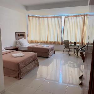 a hotel room with two beds and a table and a desk at Jomtien Hostel 3 in Jomtien Beach