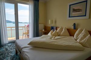 a bed in a hotel room with a large window at Hotel Seewirt in Maria Wörth