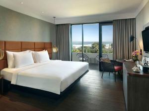 a hotel room with a large bed and a balcony at Pullman Bali Legian Beach in Legian