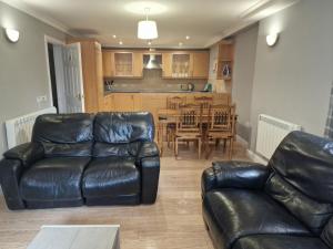 a living room with a leather couch and a dining room at Tees Valley Apartments in Middlesbrough