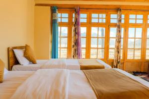 two beds in a room with windows at Astrostays at Pangong Lake in Spangmik