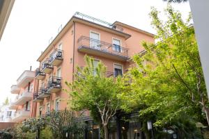 a pink building with trees in front of it at Hotel Villa Merope with free coffee in Rimini