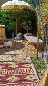 een patio met een paraplu en een tapijt bij Studio de charme avec jardin privatif à 10 minutes des plages in Le Beausset