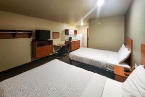 a hotel room with two beds and a television at Suburban Studios in Dickinson