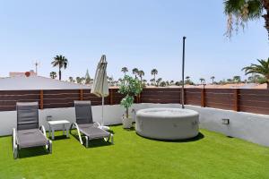 a patio with a table and chairs and an umbrella at Casa Luna Kingbed and Jacuzzi in Maspalomas