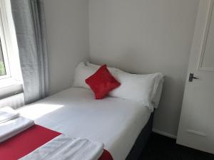 uma pequena cama com uma almofada vermelha em cima em Washington's Diamond 3 Bedroom House Sleeps 6Guest em Washington