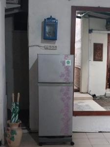a refrigerator in a kitchen with a blue picture on the wall at Omah Ndanu Homestay in Yogyakarta