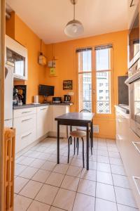 cocina con paredes amarillas, mesa y sillas en *LarDéco* Central ville & Parking en Clermont-Ferrand