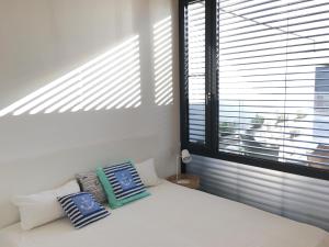 a bedroom with a white bed and a window with blinds at Ferienhaus am See Neusiedl in Neusiedl am See