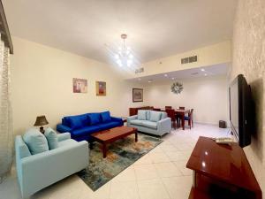 a living room with blue couches and a dining room at Lovely 2BR Al Deyafa in Dubai