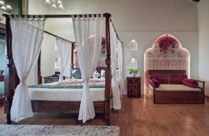 a bedroom with a four poster bed with a canopy at Malhar Machi Mountain Resorts in Mulshi