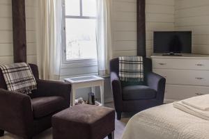 een slaapkamer met 2 stoelen en een bed en een tv bij Lossirannan Kartano in Huutotöyry