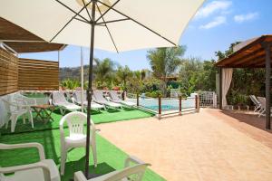 eine Terrasse mit einem Sonnenschirm und Stühlen sowie einem Pool in der Unterkunft Casa Las Flores in Moya