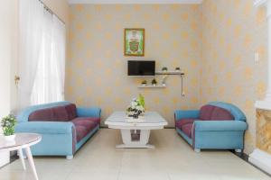 a living room with two blue chairs and a table at RedDoorz At Ralica Grand Palladium Medan in Medan