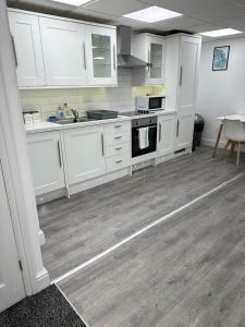 a kitchen with white cabinets and a wooden floor at Huge studio close to city centre with free secure parking in Leeds