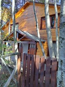 una casa de madera con una valla delante en La Casita del Bosque en Ushuaia