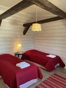 two beds in a room with red sheets at Lossirannan Kartano in Huutotöyry