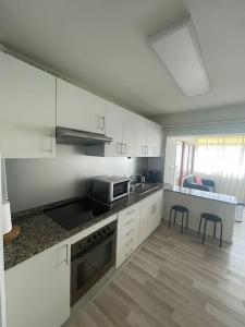 uma cozinha com armários brancos e uma bancada em Vibes Coruña-Paz 16 em Culleredo
